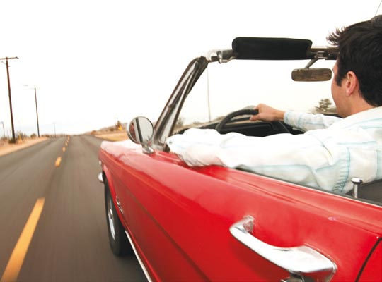 Hombre conduciendo un descapotable por la carretera