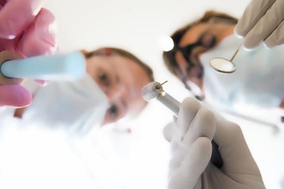 Dentista y enfermera trabajando en la boca del paciente