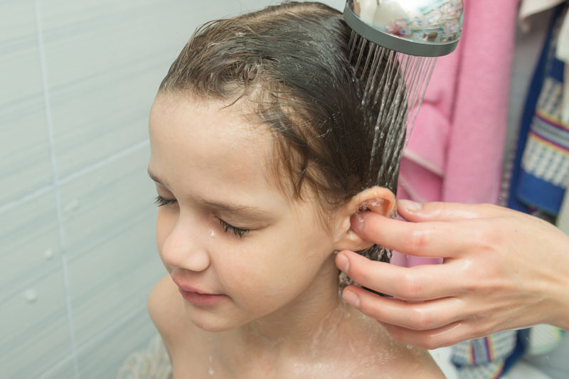 madre lava la oreja a niña en la ducha